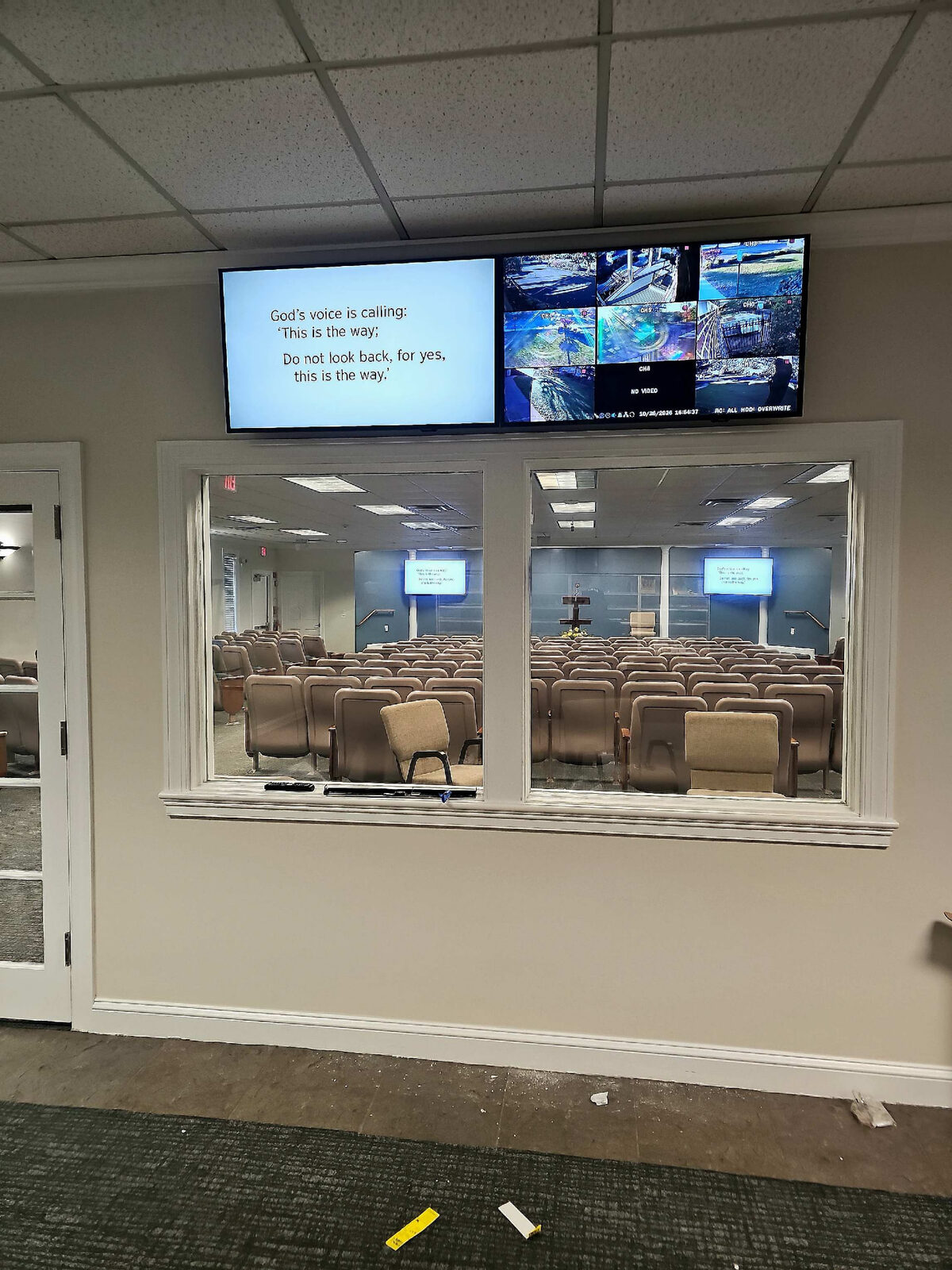 Two displays mounted above a sound booth, showing lyrics and camera feeds