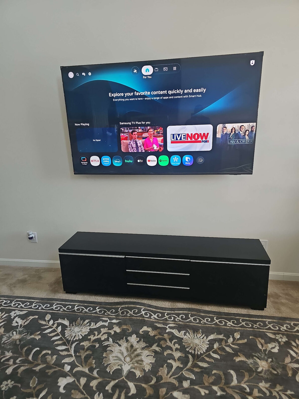 Samsung TV wall-mounted above a media console in a living room